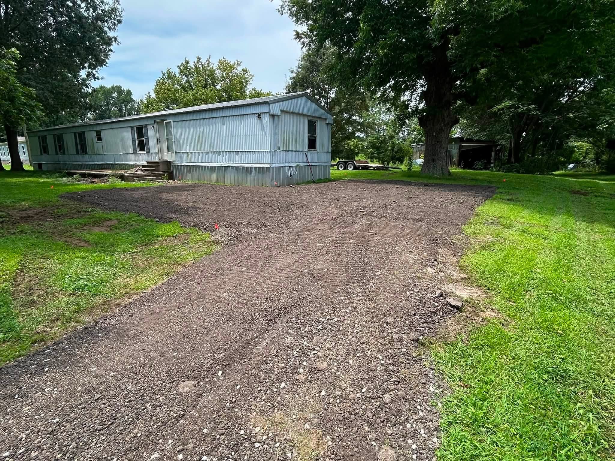 Finished gravel parking pad beside a manufactured home